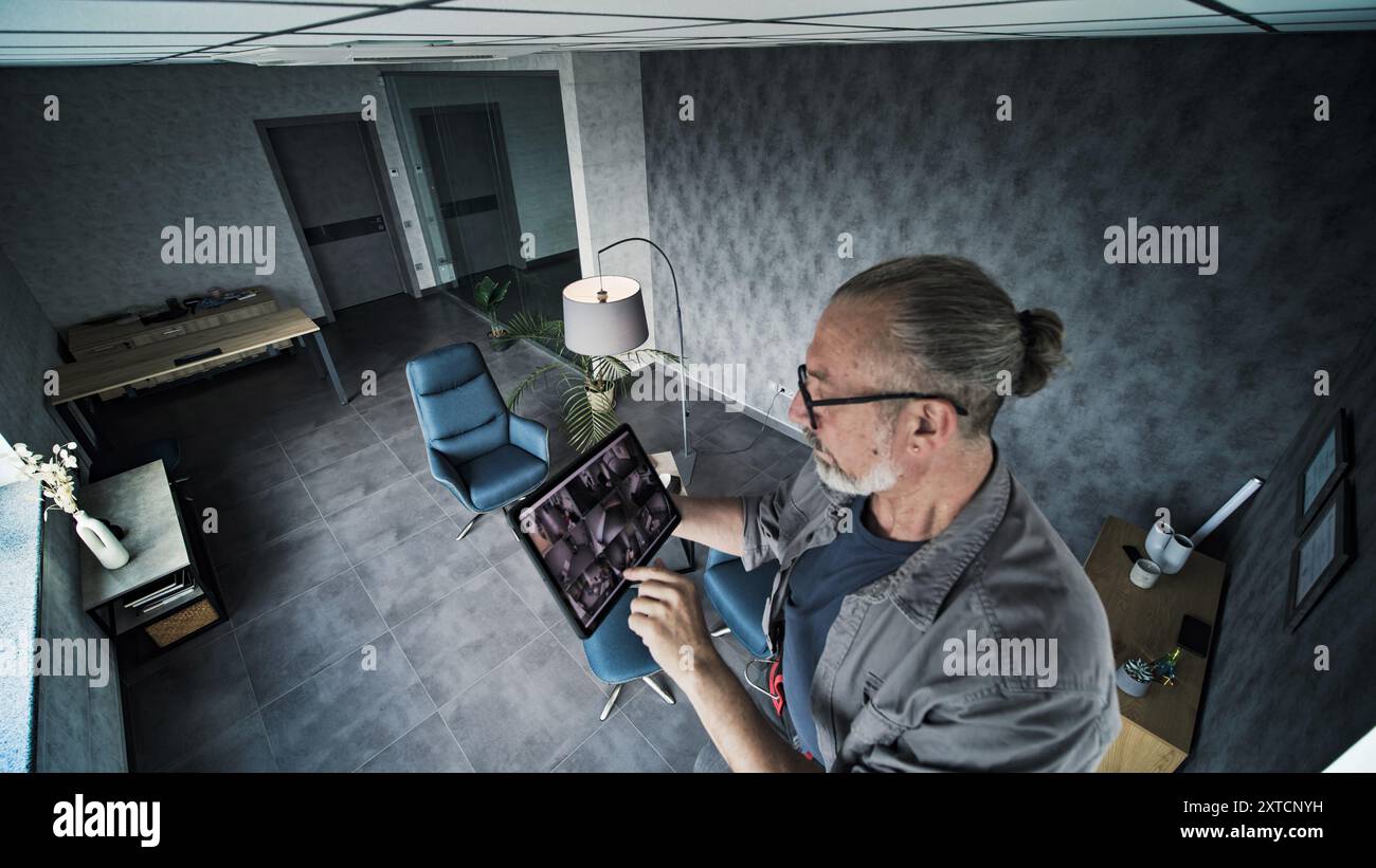 Male mature technician adjusts angle of CCTV camera, uses tablet ...