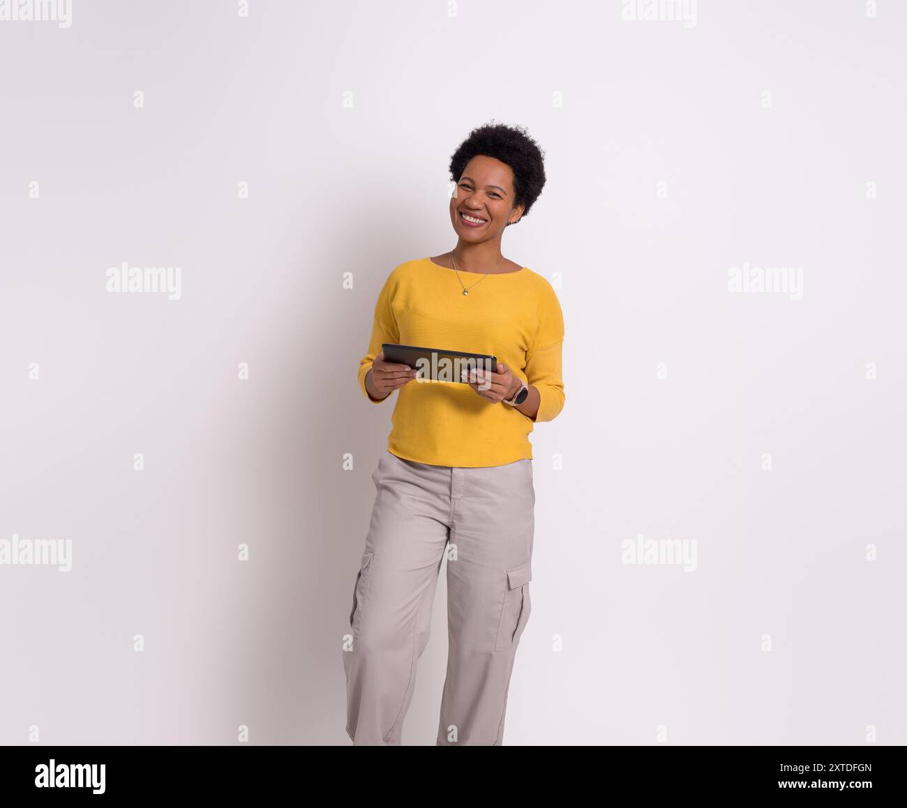 Portrait of happy businesswoman using digital tablet and standing confidently over white background Stock Photo