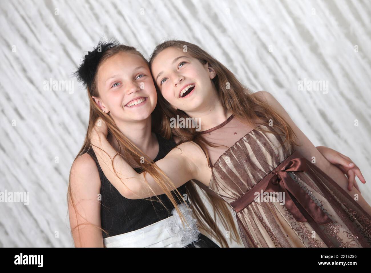 portrait of two pretty cheerful preteen girls in elegant dresses on ...
