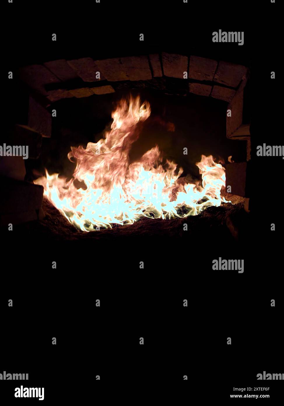 Flames from biofuel combustion blaze inside a burner of a steam boiler, showcasing the heat generator's refractive brick lining. Stock Photo