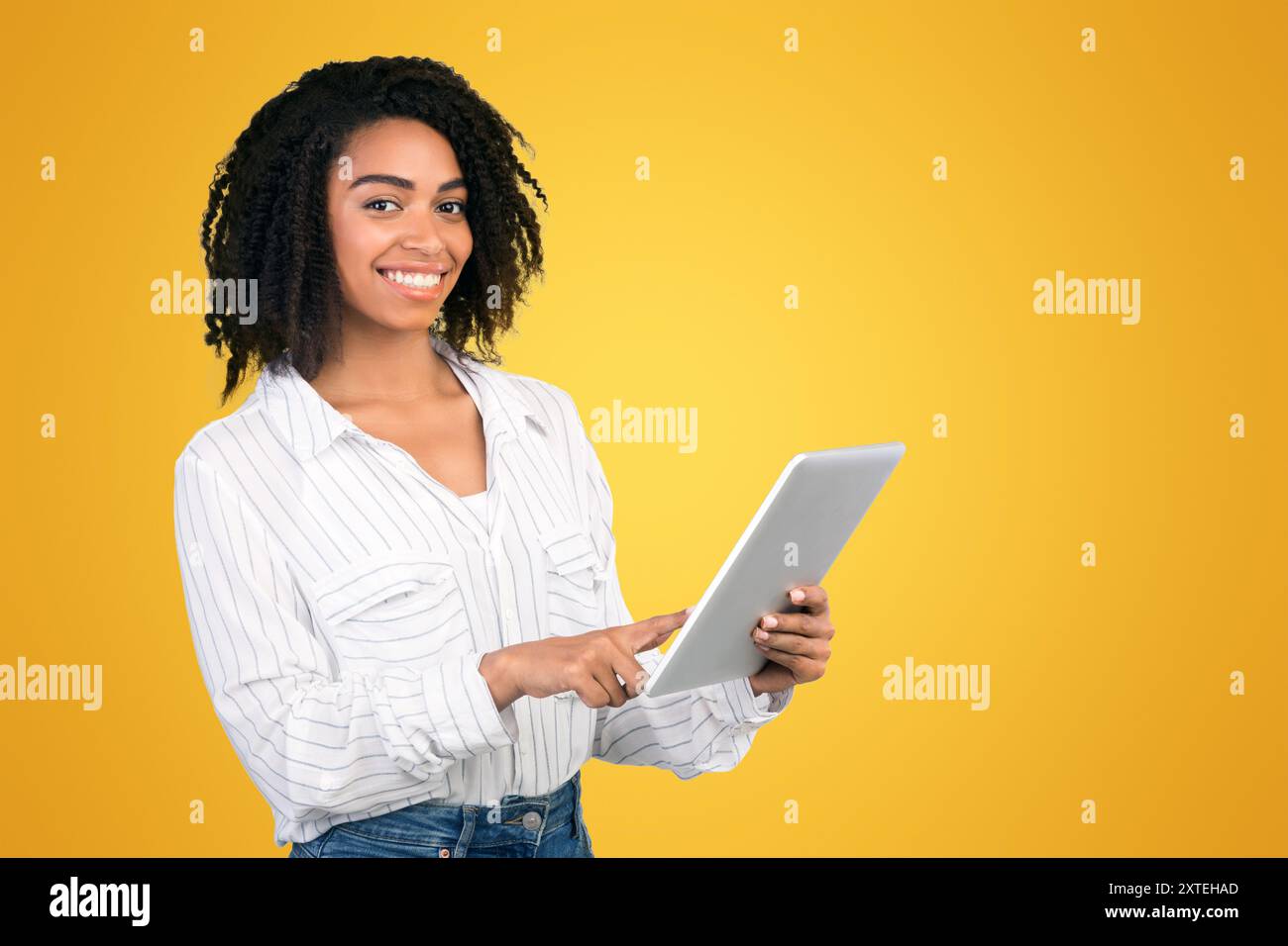 Smiling black girl standing with tablet at studio Stock Photo