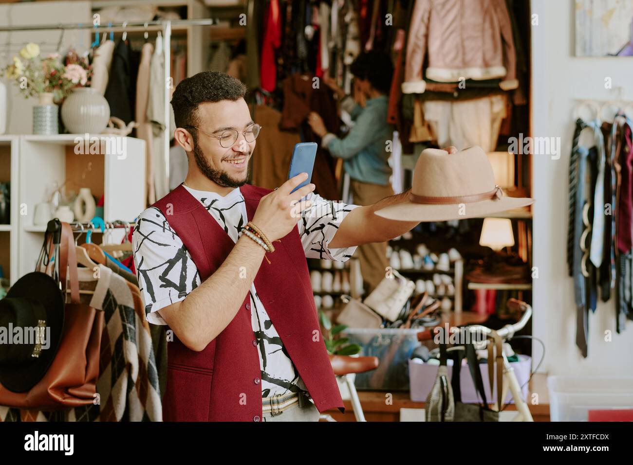 Smiling Man Holding Hat and Using Smartphone Stock Photo