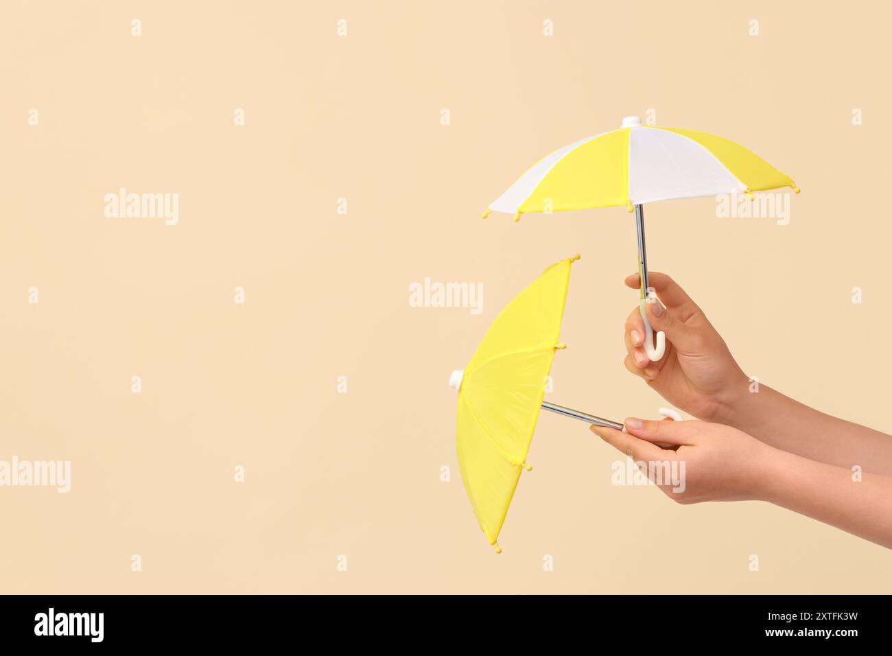 Female hands with different mini umbrellas on beige background Stock Photo