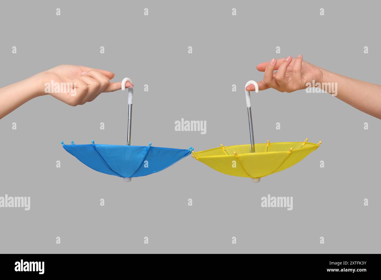 Female hands with different mini umbrellas on grey background Stock Photo