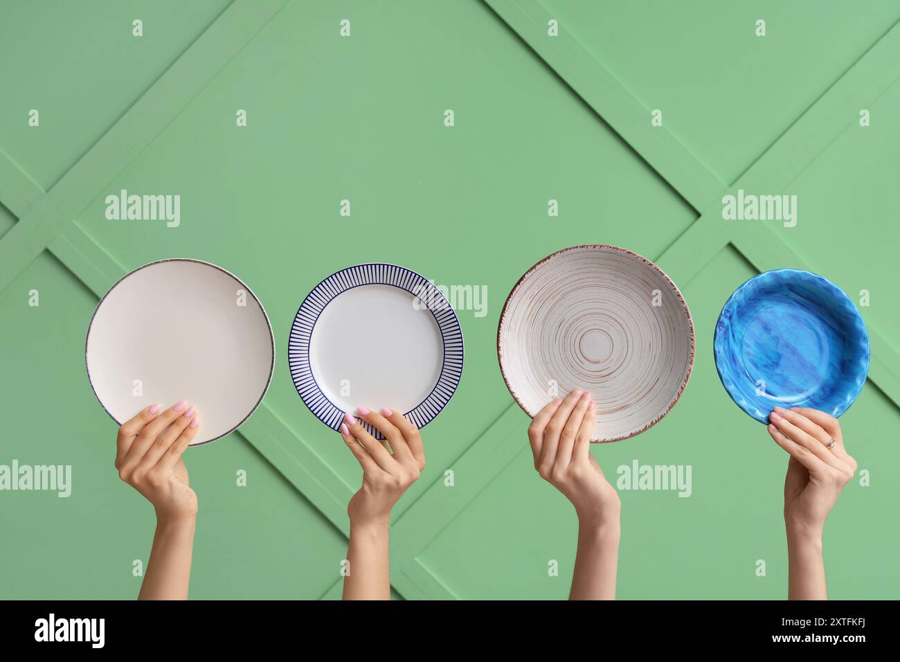 Hands holding empty plates on green background Stock Photo