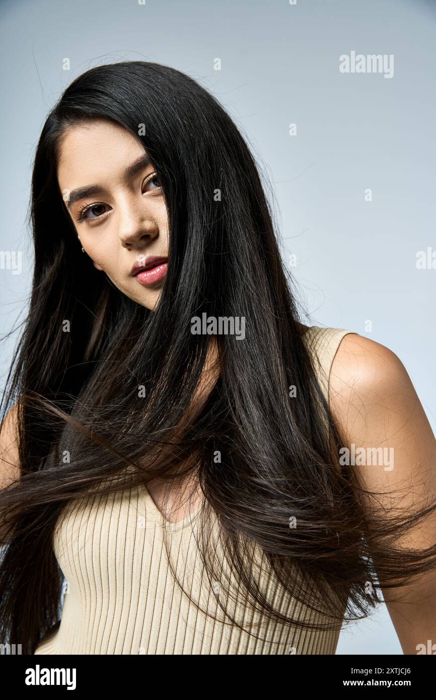 A young woman with long black hair poses for a photograph, her hair ...