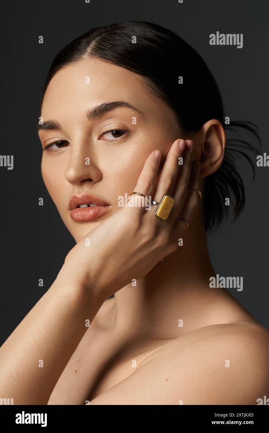 A close-up portrait of a young brunette woman with golden rings on her ...