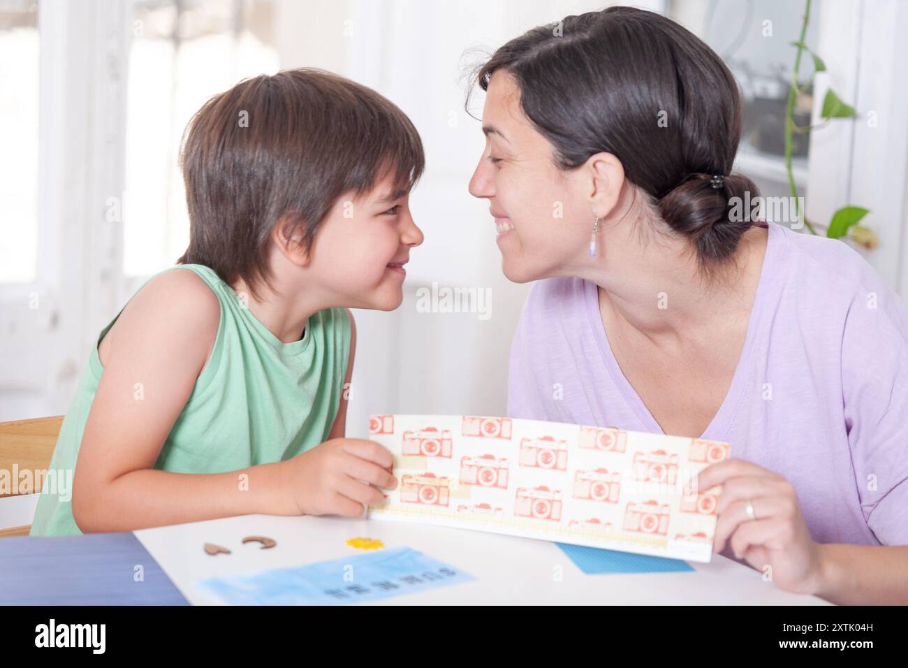 Mother and son look at each other tenderly while doing handicrafts. Stock Photo