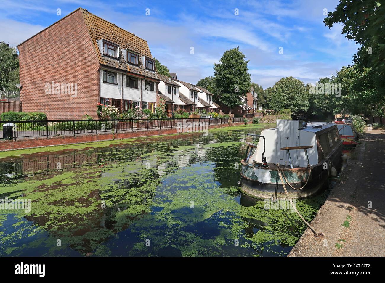 The Regents Canal near Mile End in East London north of Limehouse Basin. Shows moored houseboats and waterside housing on Union Drive. Stock Photo