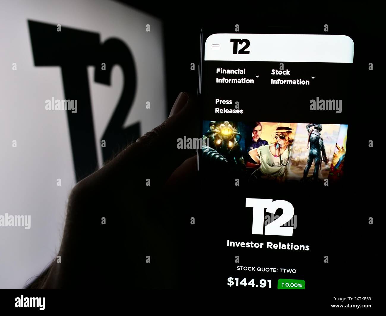 Person holding cellphone with website of US gaming company Take-Two Interactive Software Inc. in front of logo. Focus on center of phone display. Stock Photo