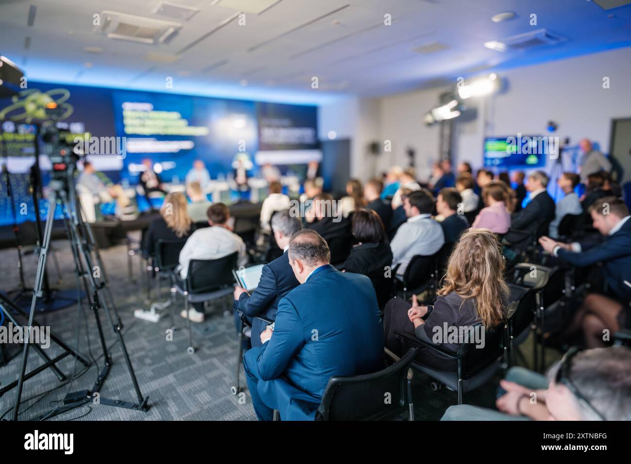 Business conference with a diverse audience and expert panel discussing innovations and strategies in a modern conference hall. Stock Photo