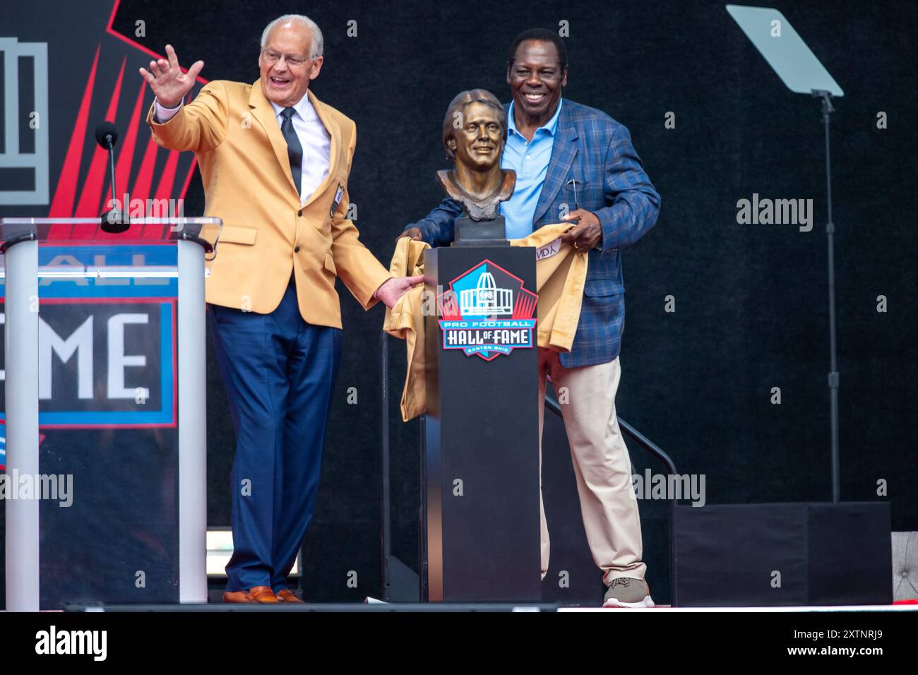 Former Denver Broncos linebacker Randy Gradishar unveils the ceremonial sculpture bust with presenter former teammate Tom Jackson during the Pro Football Hall of Fame Enshrinement Ceremony at Tom Benson Stadium in Canton, OH on Aug 3, 2024. (Max Siker / Image of Sport) Stock Photo