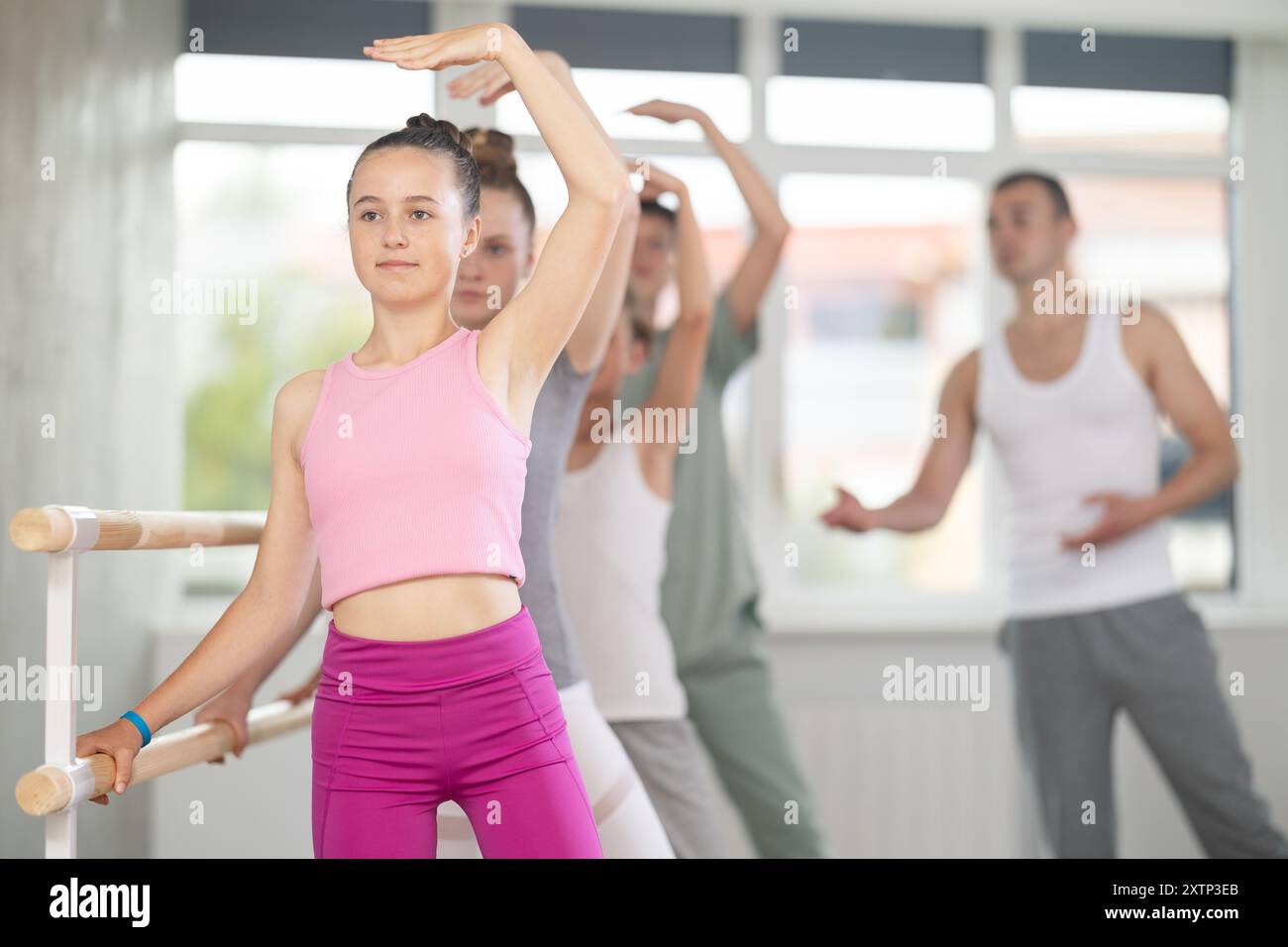 Girl during group class perform third position under male teacher ...