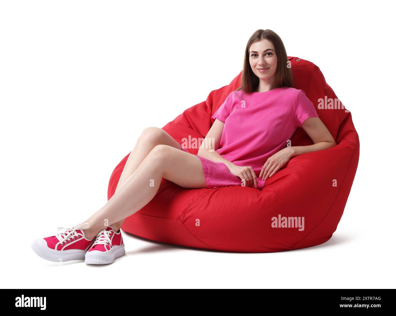 Beautiful young woman sitting on red bean bag chair against white ...