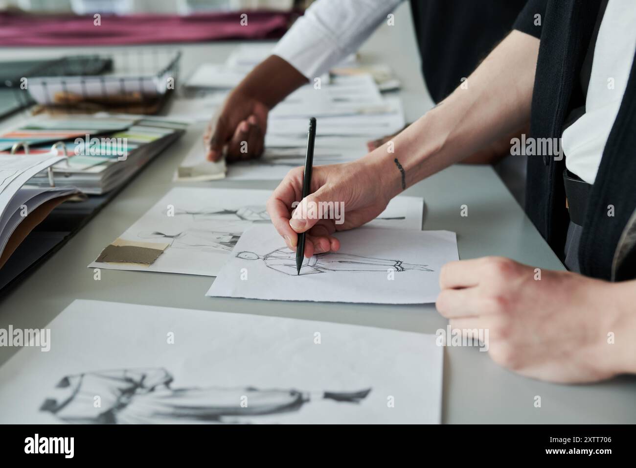 Hand of young unrecognizable male fashion designer with pencil drawing ...