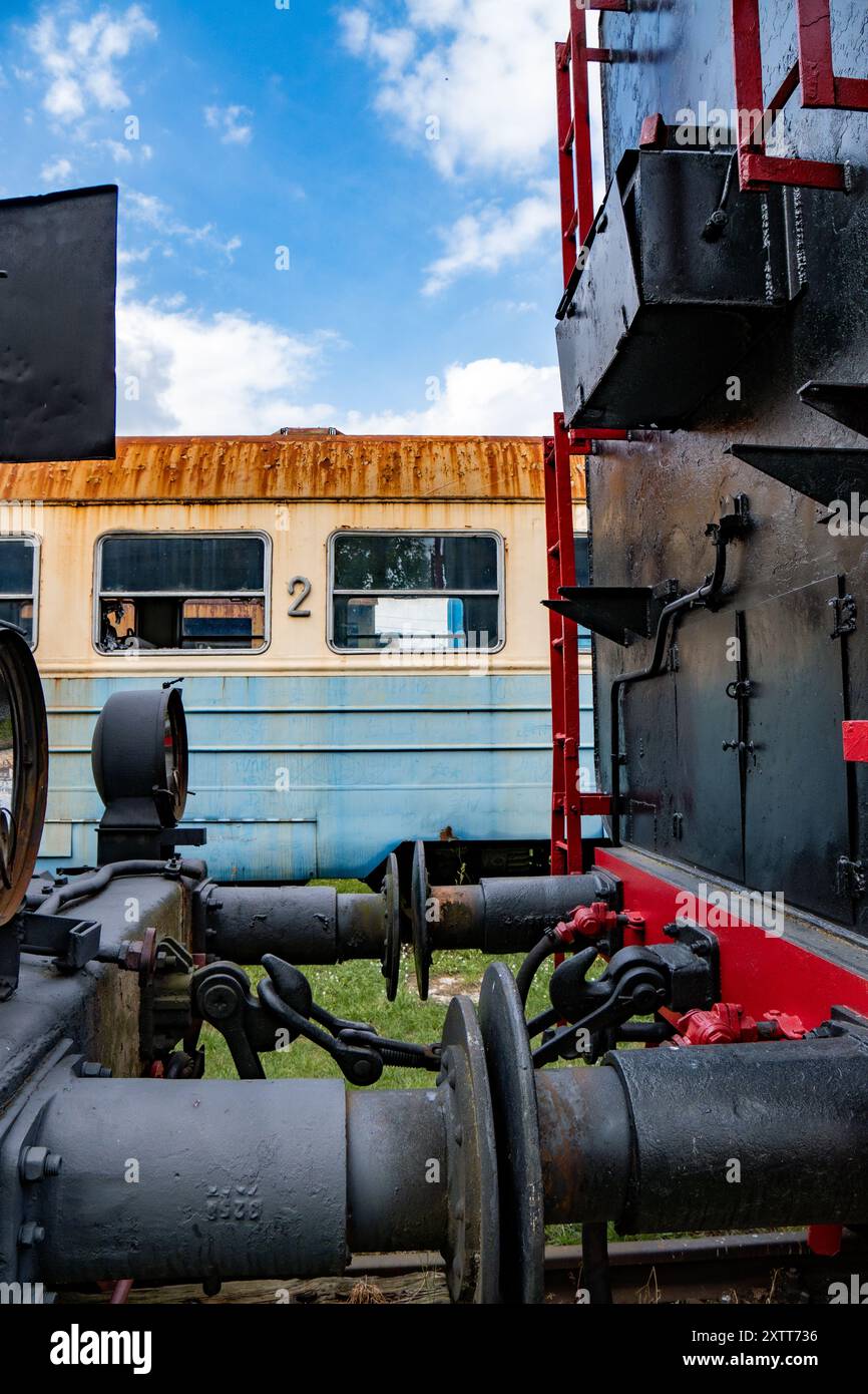 Detailed view of an old rusty steam train and vintage train carriage under a blue sky Stock Photo