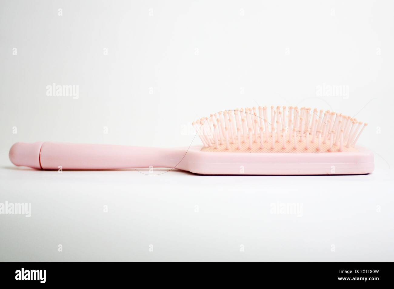 Hairbrush with strands of black hair stuck in it isolated on white background Stock Photo