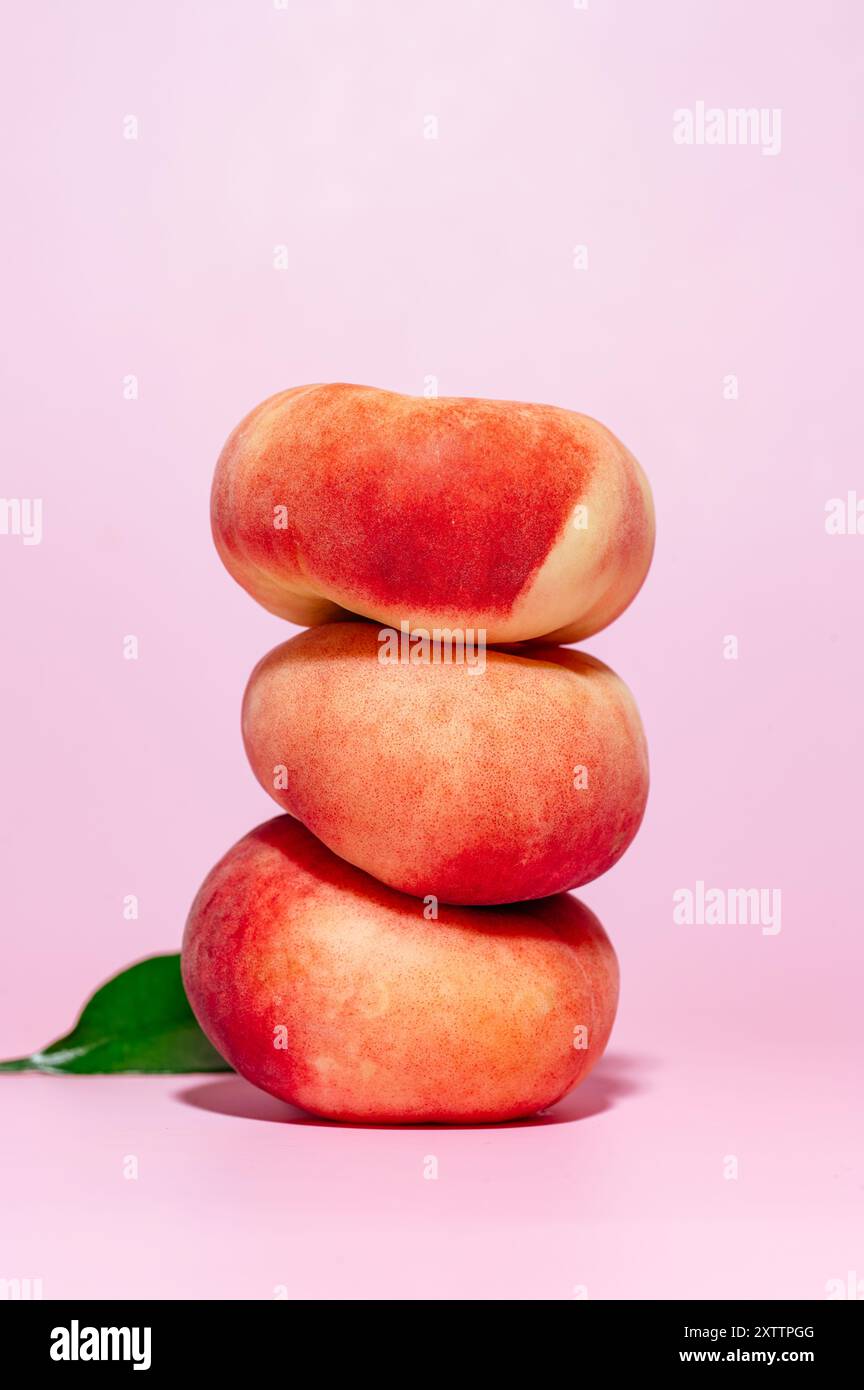 three ripe peaches on a pink background. Stock Photo