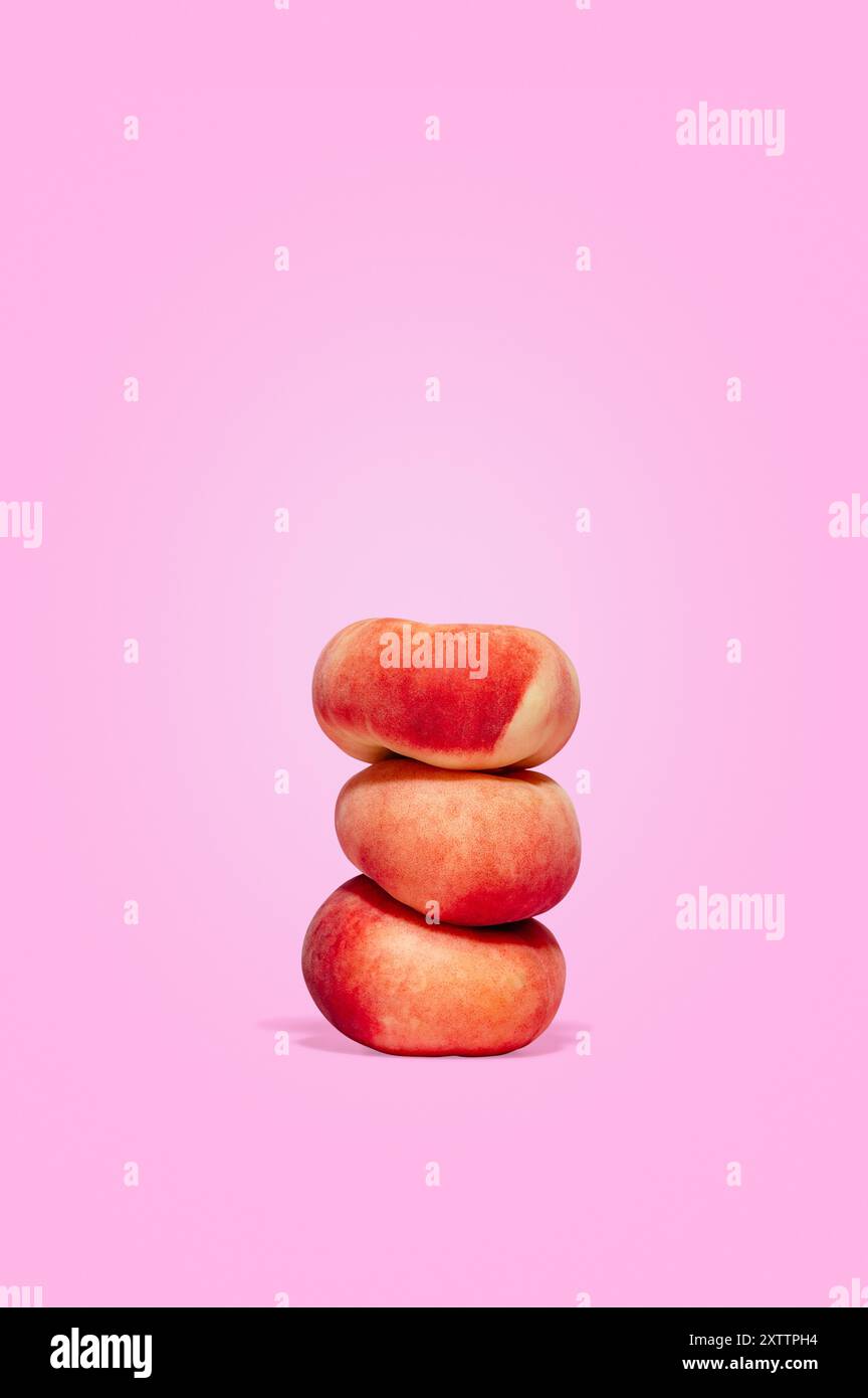 three ripe peaches on a pink background. Stock Photo