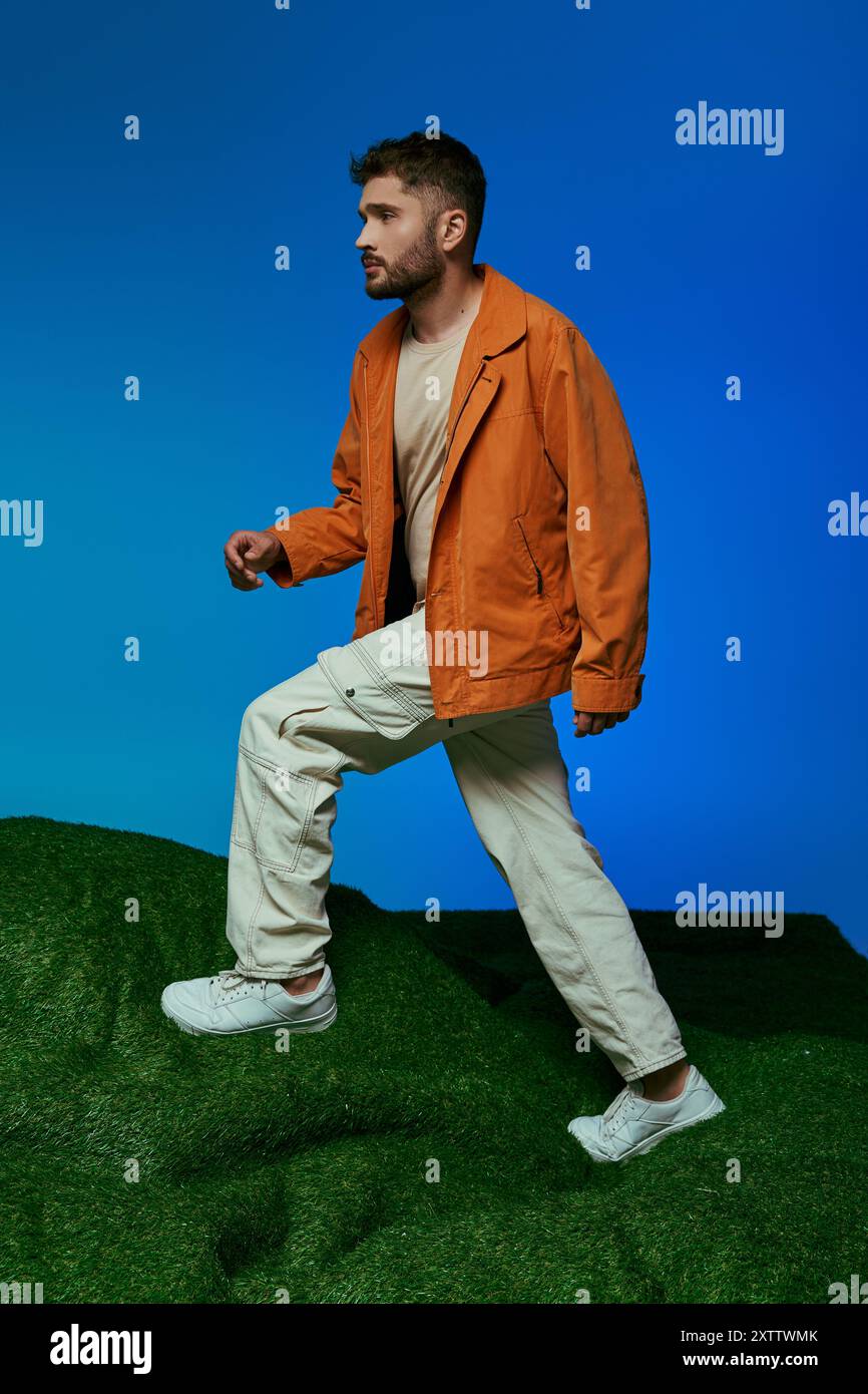 A man in an orange jacket walks on a green hill Stock Photo - Alamy