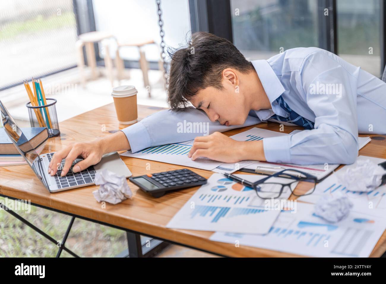 Tired and overworked young businessman falling to sleep while working late in his office Stock Photo