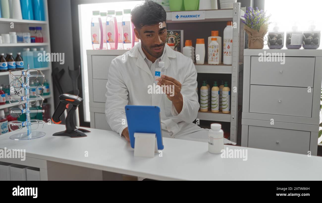 Young man in a pharmacy shop during a videoconference, holding a pill bottle in his hand while wearing a white lab coat. Stock Photo