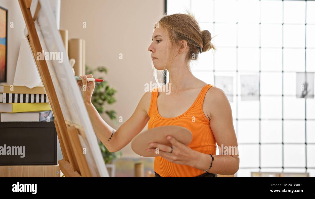 Focused young woman painting on canvas in a bright art studio Stock ...