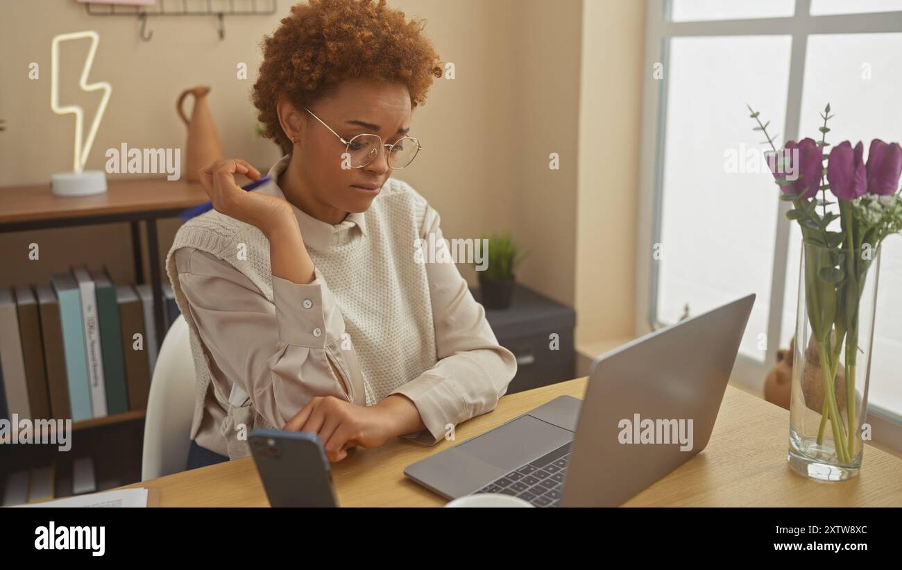 A contemplative african american woman with glasses using a laptop and ...