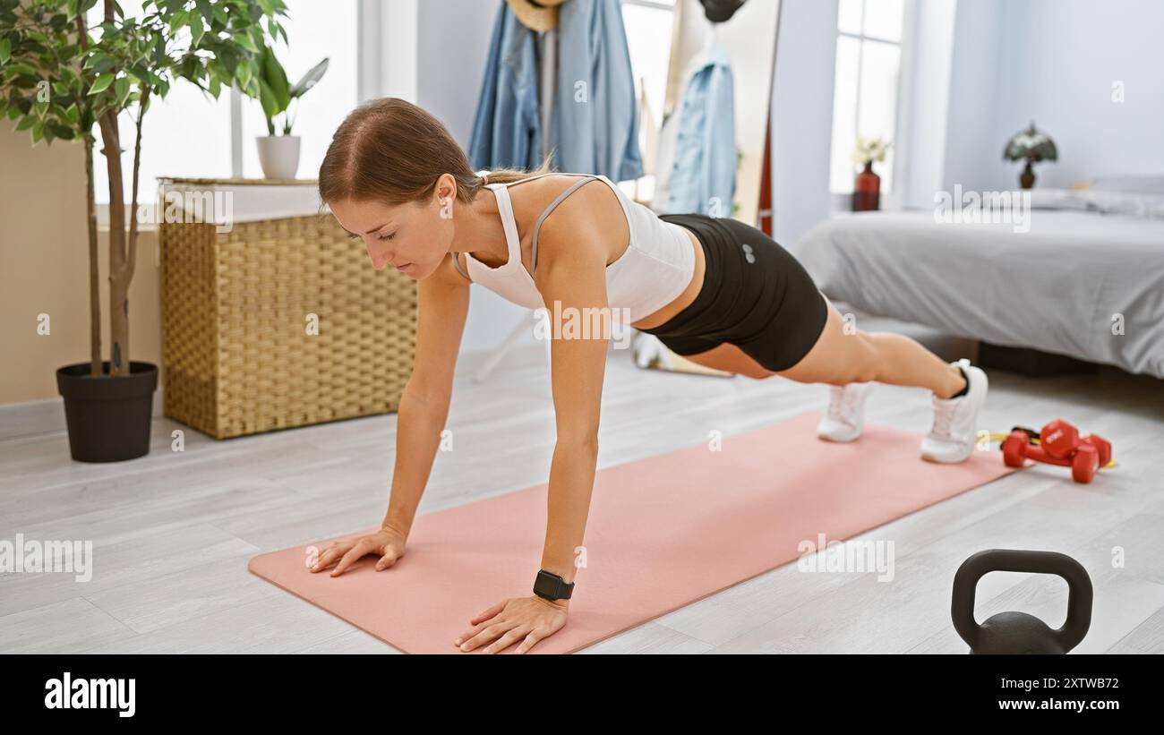 Focused young woman performing a plank exercise in a neat bedroom ...