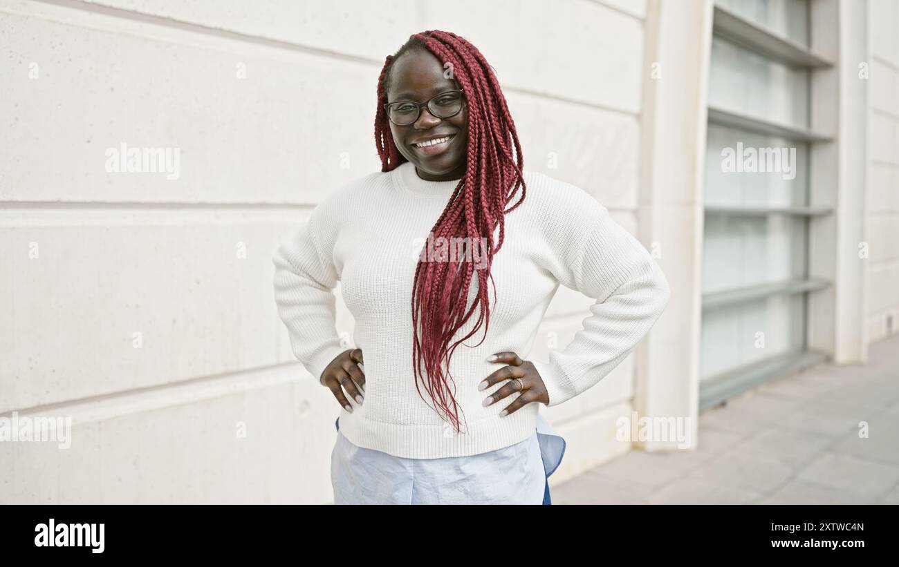 African american woman with braids smiling outdoors in an urban setting ...