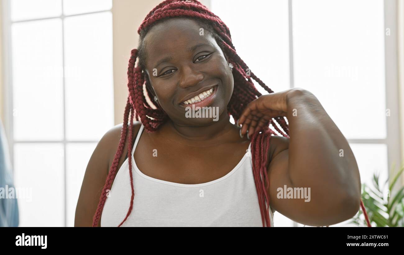 A cheerful african american woman with red braids posing indoors in a ...