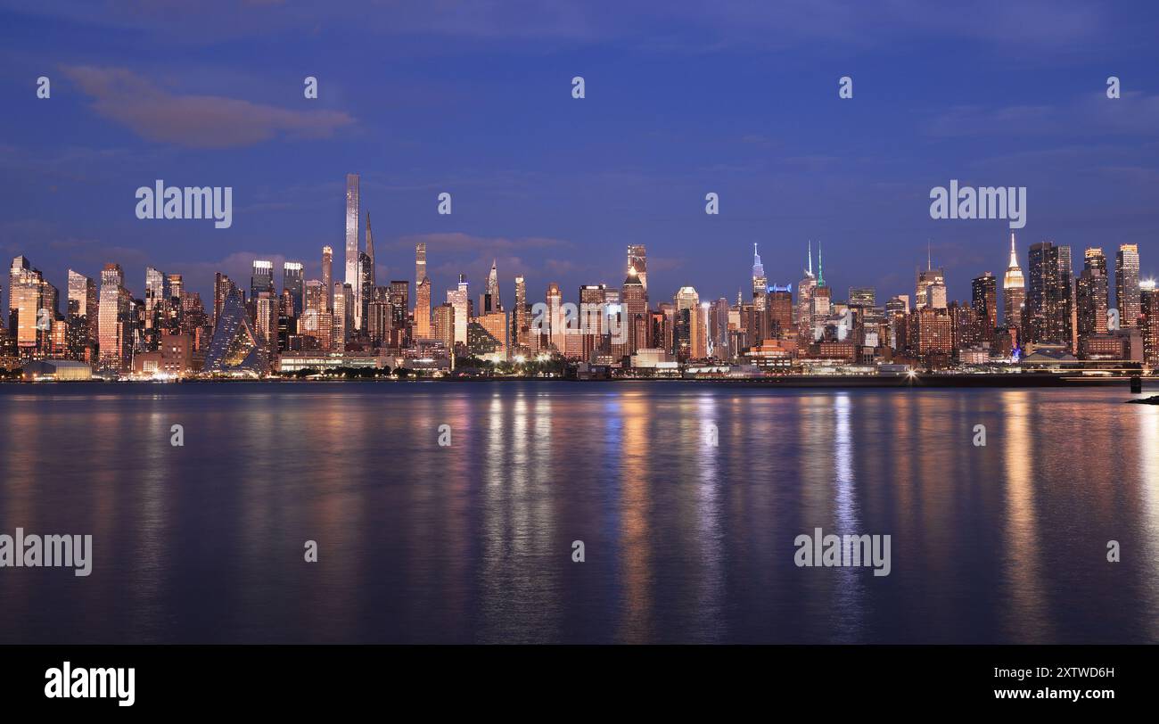 New York City skyline illuminated at dusk, view from Hudson River, USA Stock Photo