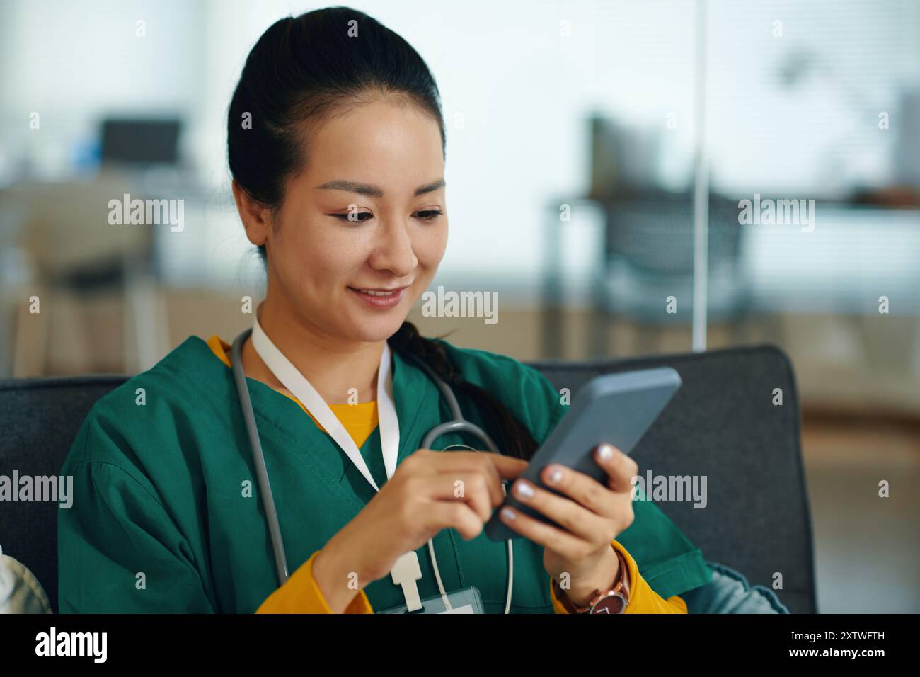 Smiling Nurse Using Smartphone in Hospital Setting Stock Photo