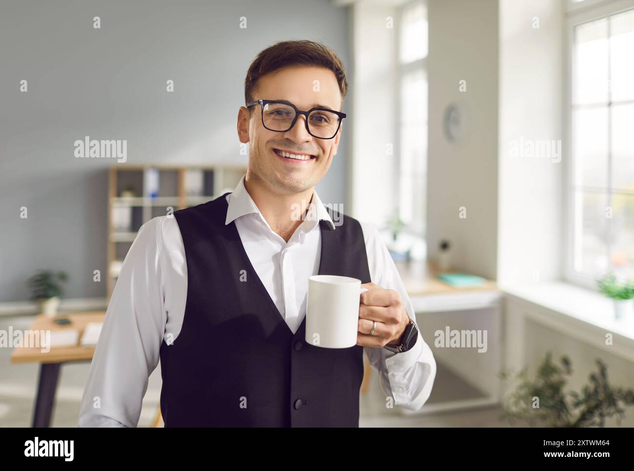 Smiling Young Businessman Enjoying Tea or Coffee Break in Office Stock Photo