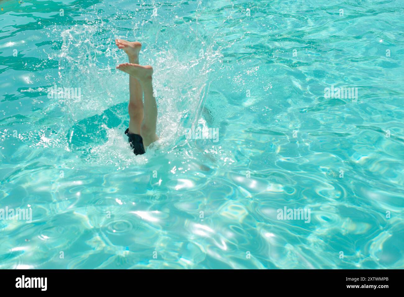 Legs submerged upside down in a clear turquoise pool creating a splash ...