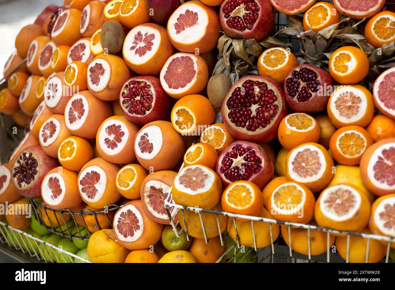 Assorted citrus fruits on display, including sliced oranges, grapefruits, and pomegranates arranged on a market stand. Stock Photo