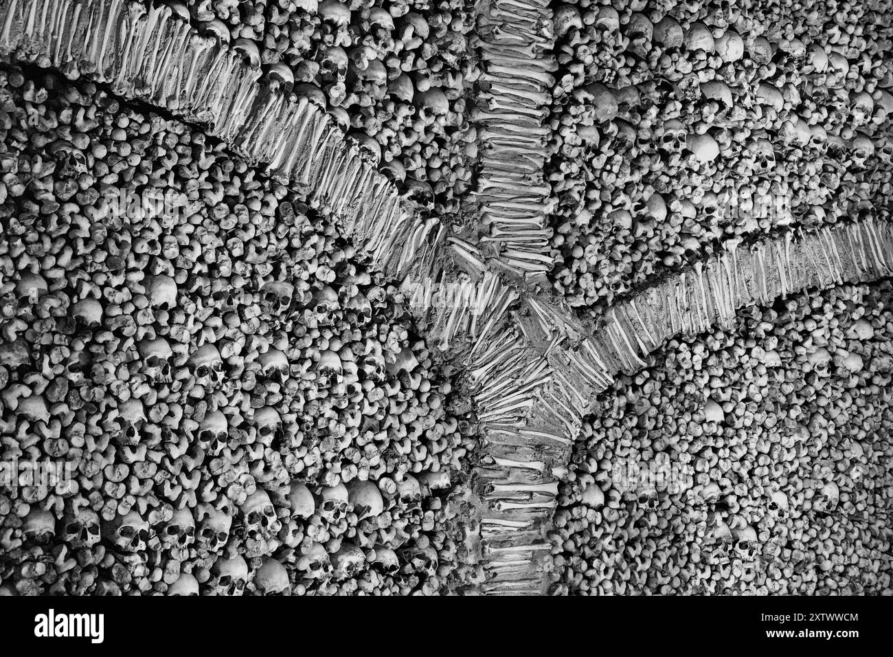 Black and white close-up of a cracked dry surface with stones and pebbles, Church of Bones, Evra, Portugal Stock Photo