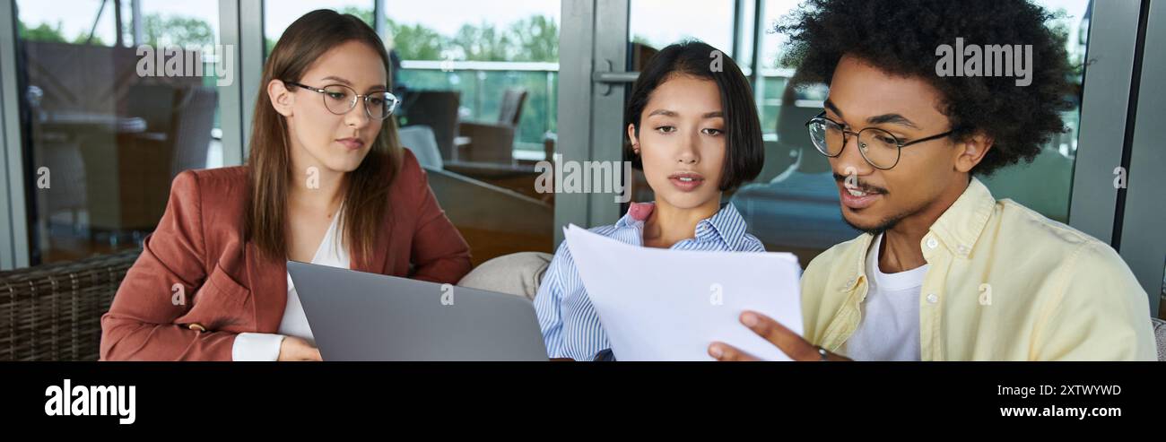 Three coworkers, chat and collaborate on the rooftop terrace during a sunny afternoon. Stock Photo