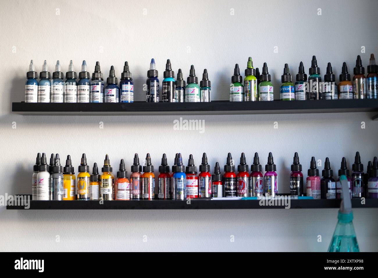 Artist selecting ink tubes from a rack of premium tattoo ink brands