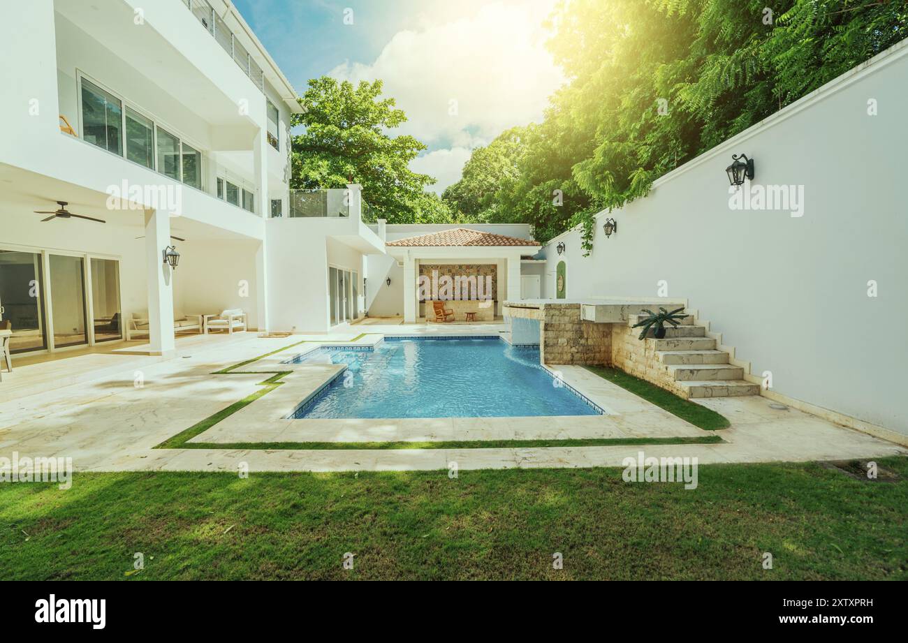 Beautiful crystal clear swimming pool in a backyard. Swimming pool surrounded by nature trees Stock Photo