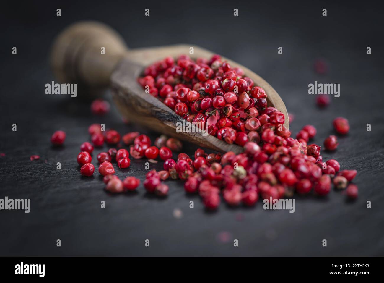 Portion of Pink Peppercorns on a rustic slate slab, selective focus, close-up shot Stock Photo