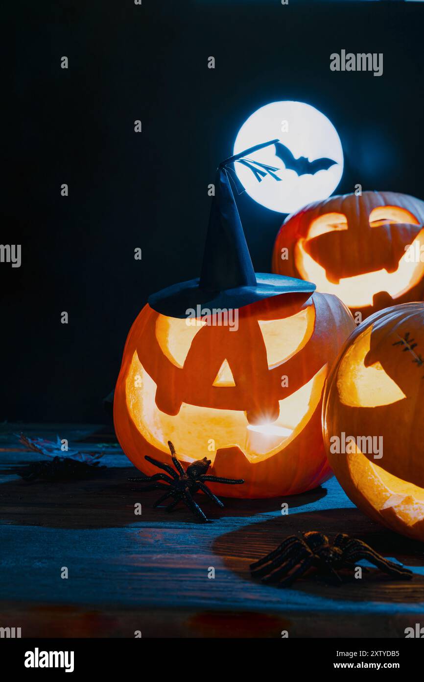 Three glowing Jack-o'-lanterns in night under a full moon with a bat ...
