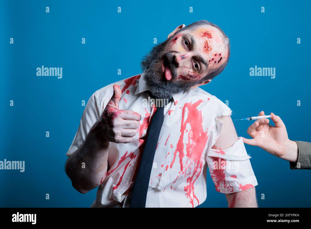 Man covered in blood and bruises receiving rabies vaccine after being attacked by feral animals, showing thumbs up sign during recovery. Wounded person getting antivenom shot, studio background Stock Photo