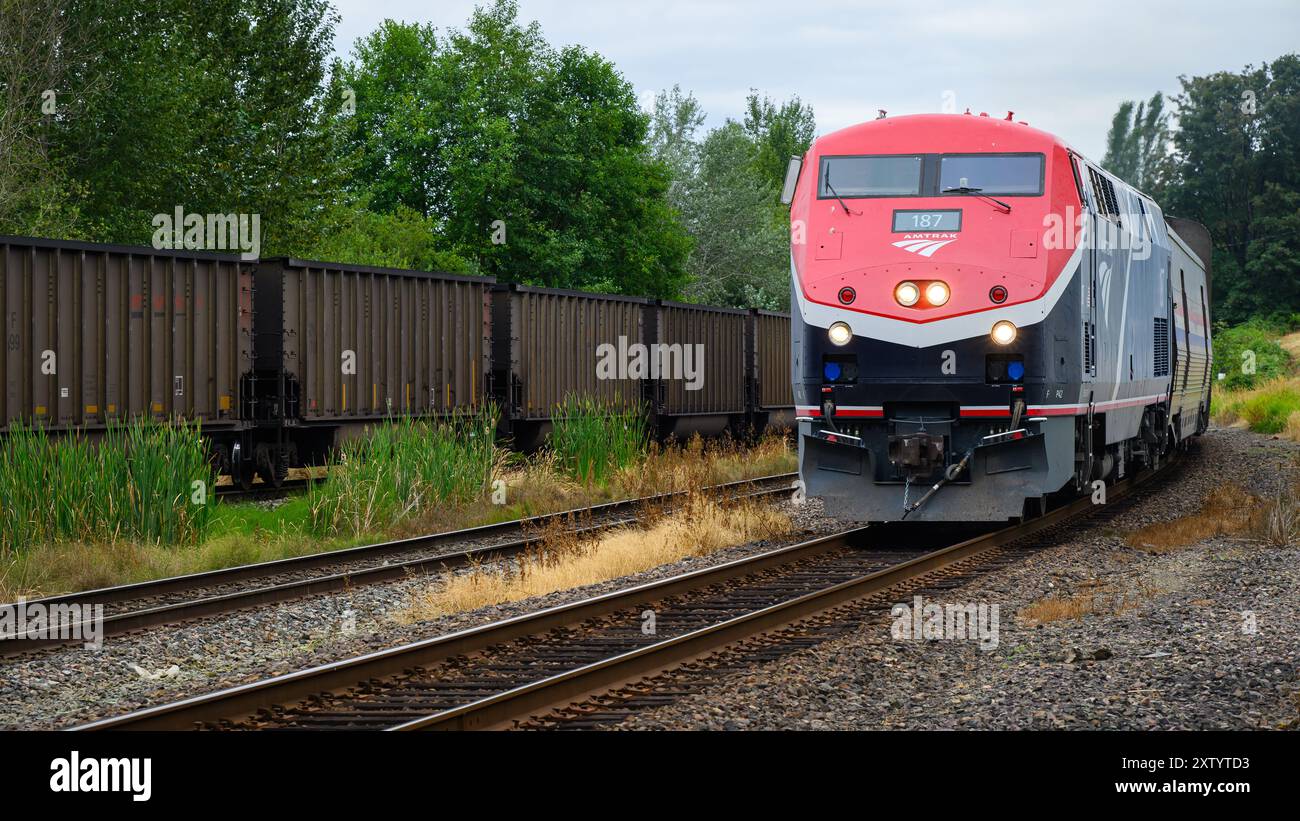 Everett, WA, USA - July 28, 2024; Amtrak Empire Builder train passing freight train with headlightsll Stock Photo