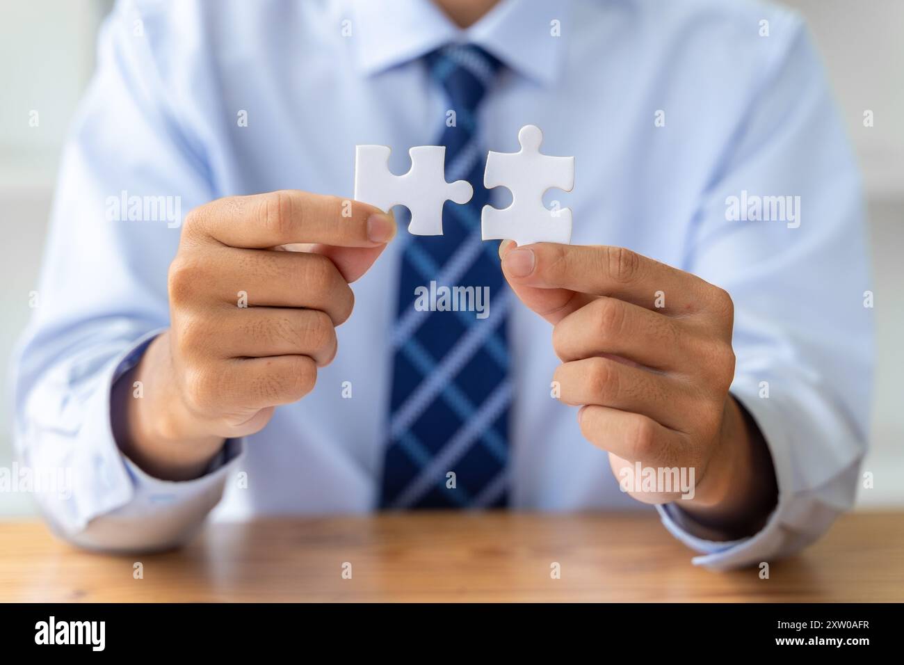 Close Up Hands Of A Businessman Holding 2 Jigsaw Puzzle Piecess Trying close-up-hands-of-a-businessman-holding-2-jigsaw-puzzle-piecess-trying