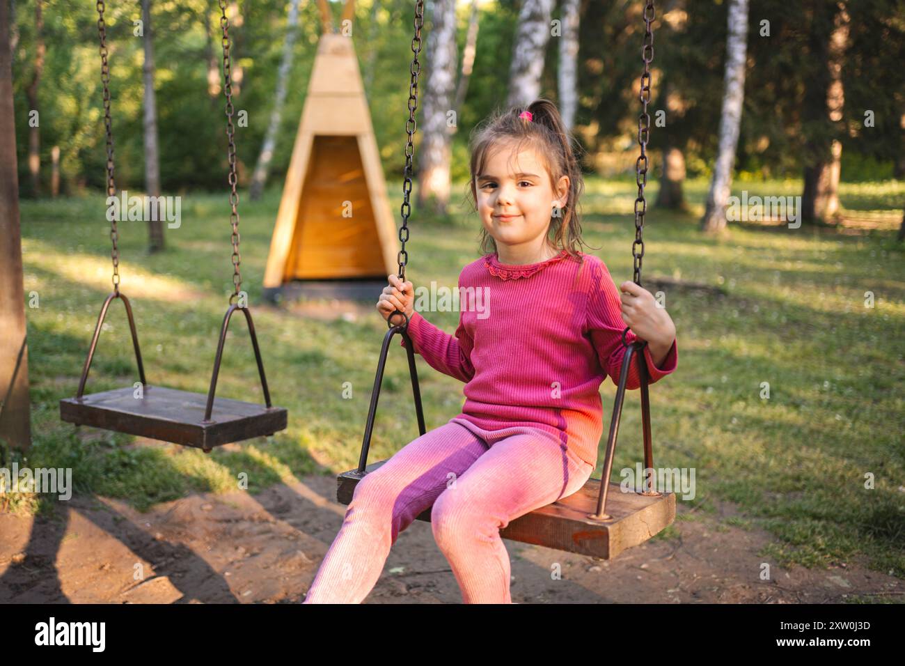 Cute smiling girl on a swing in the playground Stock Photo - Alamy