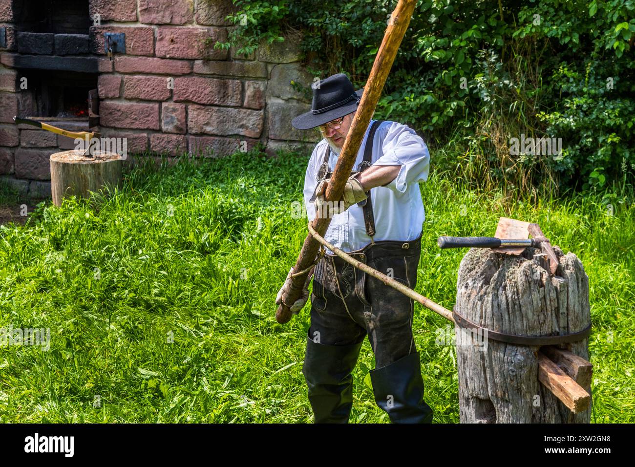 Raftsman Martin Spreng turns a heated pine trunk in the Wiedstock at the Monhardter Wasserstube near Altensteig, Baden-Württemberg, Germany. The turning rod separates the wood fibres, forming a "Wiede" – a wooden rope used to bind rafts. Rafting has been recognised as UNESCO intangible cultural heritage since 2022. Stock Photo