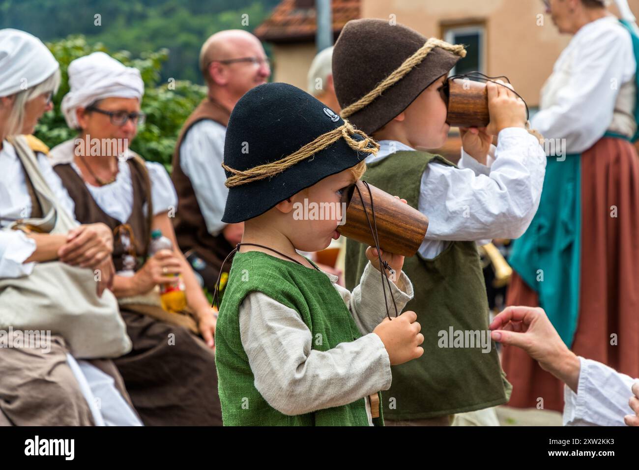 Two little boys from a traditional costume group drinking from wooden cups, 300 years of the shepherd's run in Wildberg, Black Forest. Parade at the Schäferlauf 2024 in Wildberg, Baden-Württemberg, Germany Stock Photo