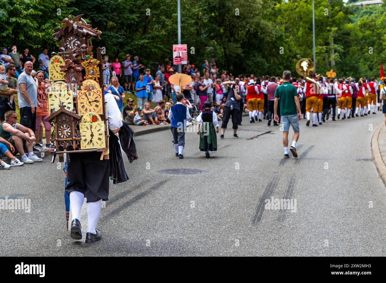 The tradition of **cuckoo clock carriers** originates from the Black Forest and goes back to the time when the famous Black Forest clocks - including the cuckoo clock - were transported and sold over long distances by so-called clock carriers on their backs. These clock carriers used a special back carrier, the "scabbard", to transport the delicate clocks safely to markets and customers. Parade at the Schäferlauf 2024 in Wildberg, Baden-Württemberg, Germany Stock Photo