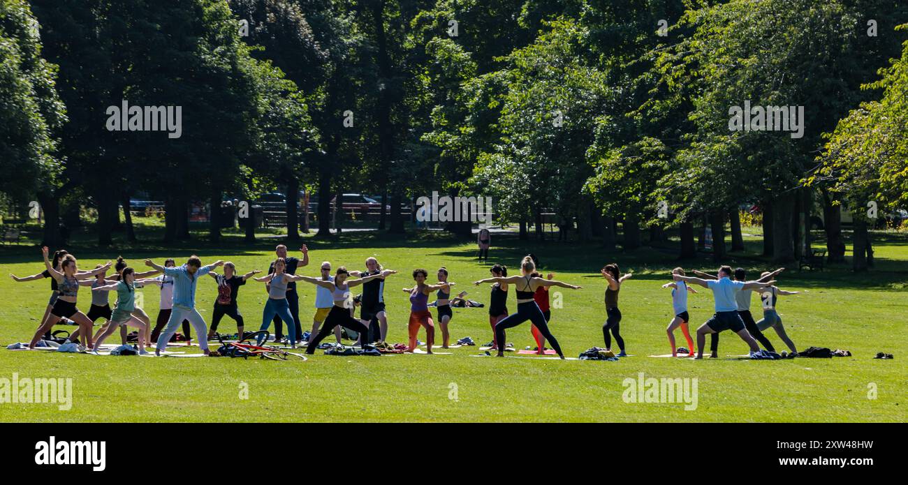 Group of people in park in Summer stretching in yoga exercise class on sunny Summer day, The Meadows, Edinburgh, Scotland, UK Stock Photo